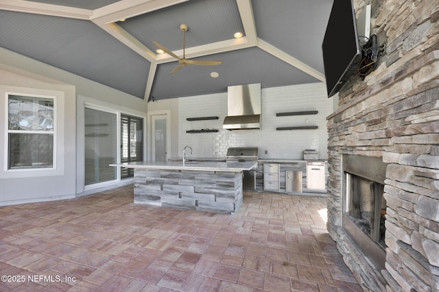 452 Deer Valley Dr, Ponte Vedra, FL 32081 - kitchen featuring wall chimney exhaust hood, an outdoor stone fireplace, light countertops, a ceiling fan, and a kitchen island with sink