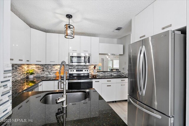 35 Turtleback Trl, Ponte Vedra Beach, FL 32082 - kitchen with appliances with stainless steel finishes, a textured ceiling, decorative light fixtures, decorative backsplash, and white cabinets