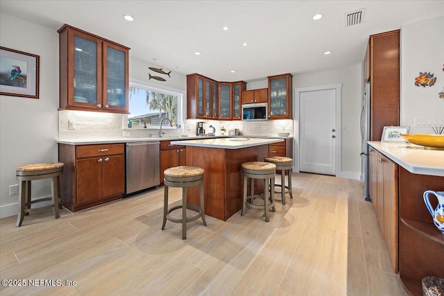 2638 W End St, Jacksonville, FL 32233 - kitchen with stainless steel appliances, a kitchen island, decorative backsplash, a breakfast bar, and light wood-style floors