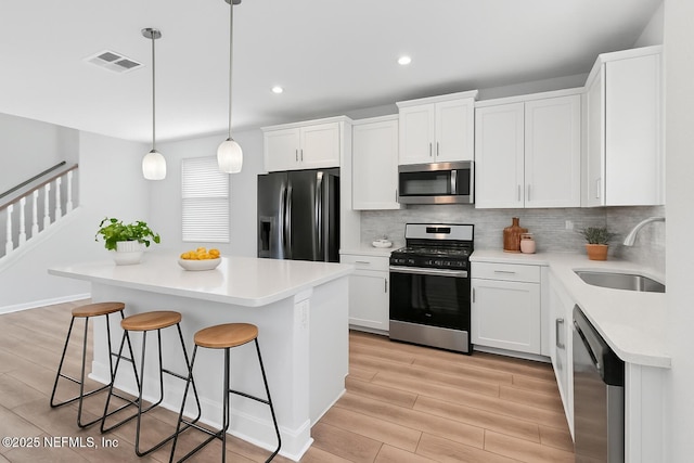117 Redbud Ln, Yulee, FL 32097 - kitchen featuring stainless steel appliances, light wood-style floors, a kitchen breakfast bar, tasteful backsplash, and light countertops