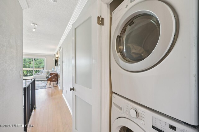 136 Sherwood Ave, Saint Augustine, FL 32084 - laundry area with stacked washing machine and dryer, a textured ceiling, light wood-style floors, and crown molding