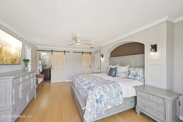 136 Sherwood Ave, Saint Augustine, FL 32084 - bedroom with a barn door, light wood-type flooring, crown molding, and ceiling fan
