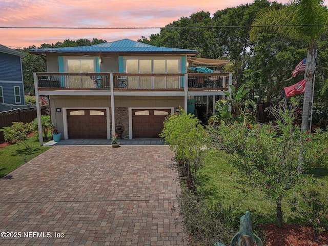 136 Sherwood Ave, Saint Augustine, FL 32084 - view of front of house featuring decorative driveway, a garage, a metal roof, and a balcony
