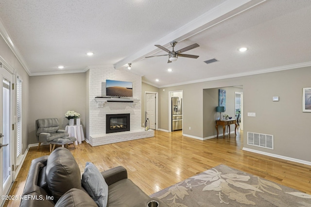 12137 Dividing Oaks Trl E, Jacksonville, FL 32223 - living area featuring a ceiling fan, light wood finished floors, a fireplace, crown molding, and a textured ceiling