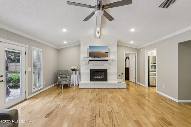 12137 Dividing Oaks Trl E, Jacksonville, FL 32223 - living area featuring a textured ceiling, light wood finished floors, a brick fireplace, a ceiling fan, and ornamental molding