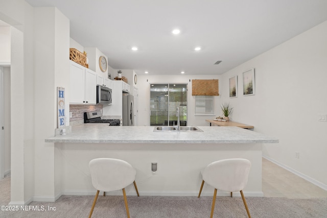 148 Stonecrest Dr, Saint Johns, FL 32259 - kitchen with stainless steel appliances, light colored carpet, a breakfast bar area, a peninsula, and light countertops