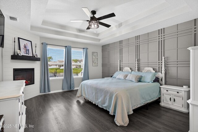 665 Flach Dr, Saint Johns, FL 32259 - bedroom featuring a tray ceiling, a fireplace, dark wood-type flooring, a textured ceiling, and ceiling fan