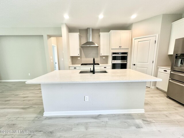 356 Bermudez Way, Saint Augustine, FL 32095 - kitchen with wall chimney range hood, appliances with stainless steel finishes, a kitchen island with sink, white cabinetry, and recessed lighting