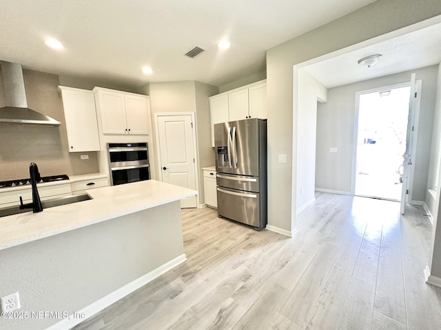 356 Bermudez Way, Saint Augustine, FL 32095 - kitchen with wall chimney range hood, appliances with stainless steel finishes, white cabinets, light wood-type flooring, and recessed lighting