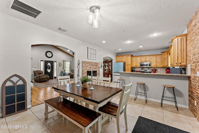 34100 Old Baldwin Rd, Callahan, FL 32011 - dining room featuring a textured ceiling, light tile patterned floors, arched walkways, recessed lighting, and a fireplace