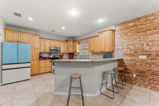 34100 Old Baldwin Rd, Callahan, FL 32011 - kitchen featuring stainless steel appliances, a textured ceiling, backsplash, a peninsula, and a kitchen bar