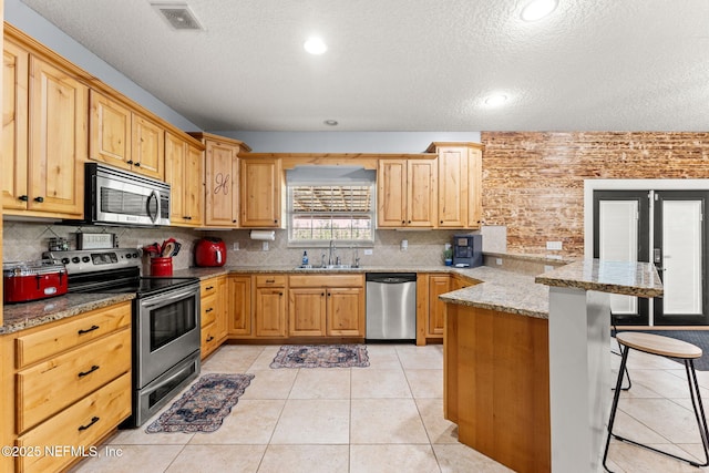 34100 Old Baldwin Rd, Callahan, FL 32011 - kitchen with stainless steel appliances, a peninsula, a kitchen breakfast bar, a textured ceiling, and tasteful backsplash