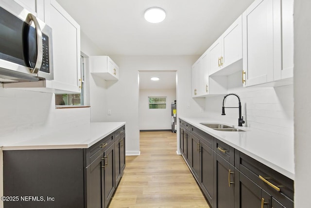 9340 Norfolk Blvd, Jacksonville, FL 32208 - kitchen featuring stainless steel microwave, white cabinets, light countertops, and light wood-style flooring