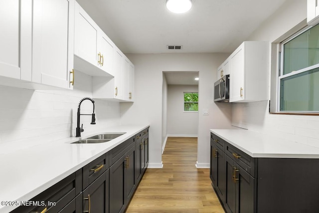 9340 Norfolk Blvd, Jacksonville, FL 32208 - kitchen with stainless steel microwave, white cabinets, light countertops, tasteful backsplash, and light wood-style floors