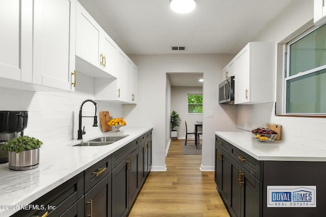 9340 Norfolk Blvd, Jacksonville, FL 32208 - kitchen with stainless steel microwave, white cabinetry, light countertops, and tasteful backsplash