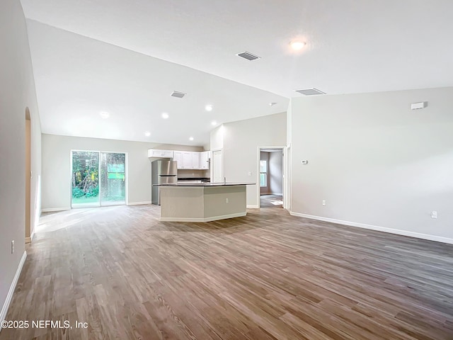 9473 N Athenia Dr, Citrus Springs, FL 34434 - unfurnished living room featuring vaulted ceiling, light wood-style flooring, arched walkways, and recessed lighting