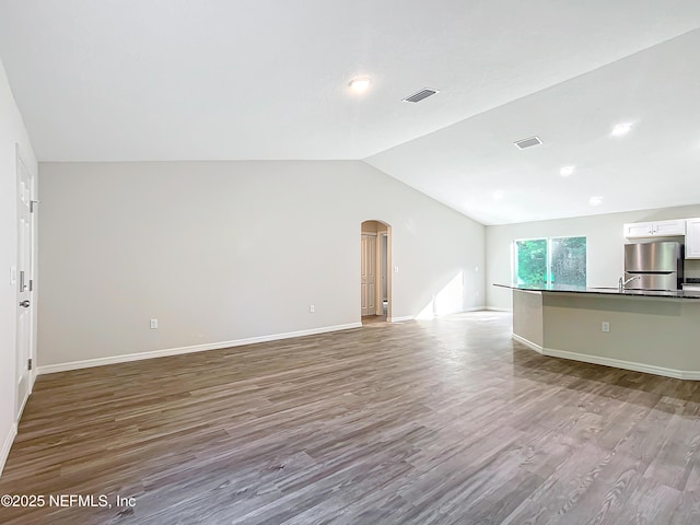 9473 N Athenia Dr, Citrus Springs, FL 34434 - unfurnished living room featuring lofted ceiling, wood finished floors, and arched walkways