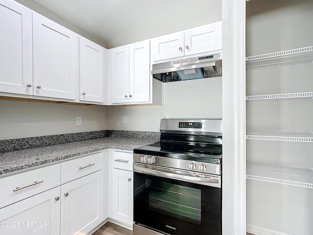 9473 N Athenia Dr, Citrus Springs, FL 34434 - kitchen with electric stove, under cabinet range hood, white cabinetry, and light stone counters
