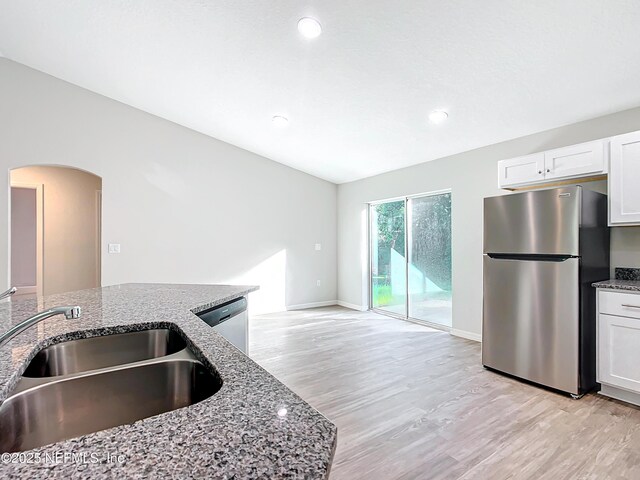 9473 N Athenia Dr, Citrus Springs, FL 34434 - kitchen featuring stainless steel appliances, stone countertops, light wood-style flooring, white cabinetry, and arched walkways