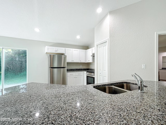 9473 N Athenia Dr, Citrus Springs, FL 34434 - kitchen with freestanding refrigerator, range, dark stone countertops, white cabinetry, and extractor fan