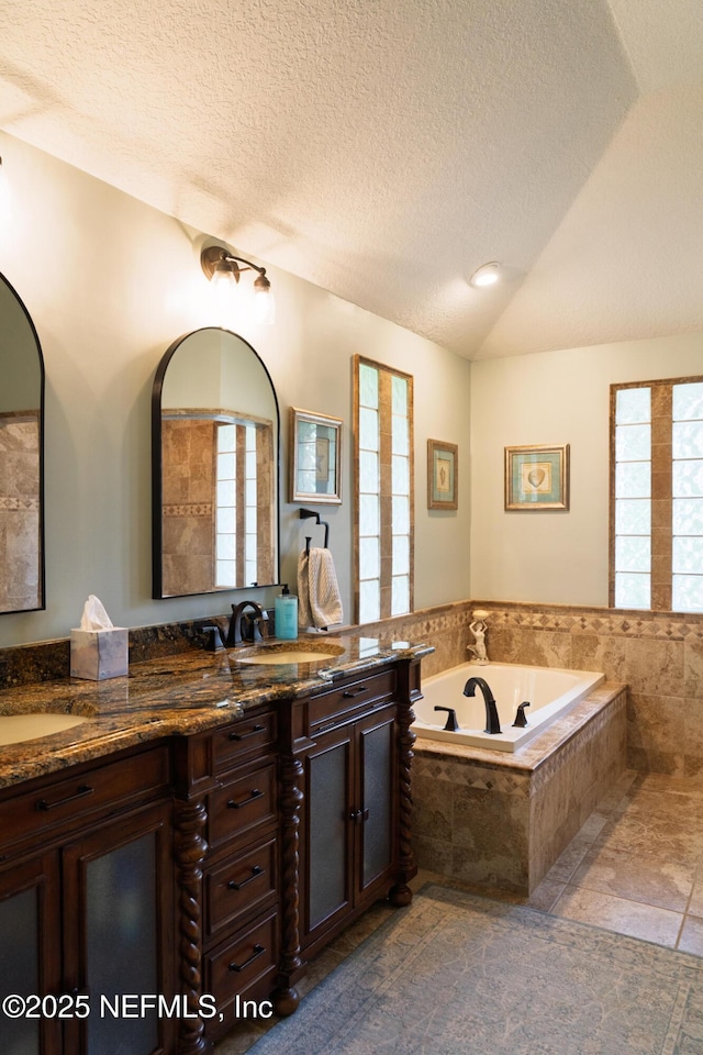 13464 Ellsworth Ln, Jacksonville, FL 32225 - full bathroom with healthy amount of natural light, double vanity, a garden tub, lofted ceiling, and a textured ceiling