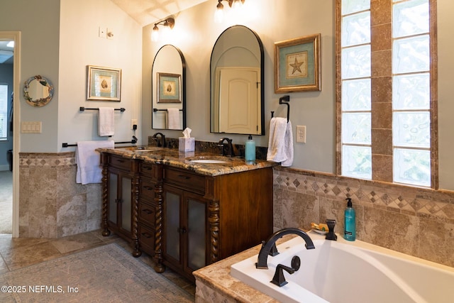 13464 Ellsworth Ln, Jacksonville, FL 32225 - bathroom with double vanity, a bath, wainscoting, and tile walls