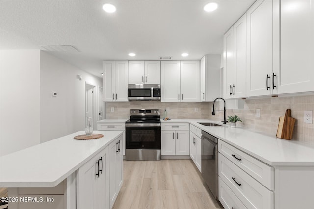 2453 Jetty Ct, Jacksonville, FL 32233 - kitchen with appliances with stainless steel finishes, light wood-style flooring, light countertops, white cabinetry, and tasteful backsplash