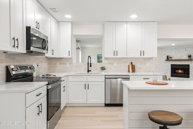 2453 Jetty Ct, Jacksonville, FL 32233 - kitchen featuring appliances with stainless steel finishes, light countertops, light wood-style floors, white cabinetry, and a kitchen bar