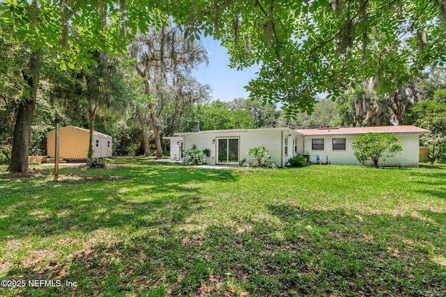 2453 Jetty Ct, Jacksonville, FL 32233 - rear view of house featuring a lawn, a shed, and view of scattered trees