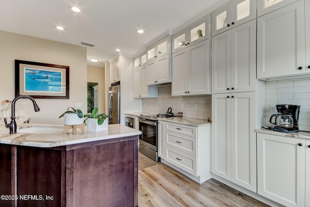 644 Sun Down Cir, Saint Augustine, FL 32080 - kitchen featuring appliances with stainless steel finishes, white cabinetry, decorative backsplash, light wood-style floors, and recessed lighting