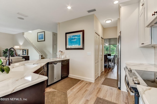 644 Sun Down Cir, Saint Augustine, FL 32080 - kitchen with stainless steel appliances, light wood-type flooring, light stone countertops, white cabinetry, and recessed lighting