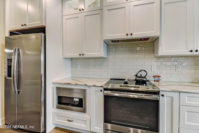 644 Sun Down Cir, Saint Augustine, FL 32080 - kitchen with stainless steel appliances, white cabinetry, backsplash, and light stone counters