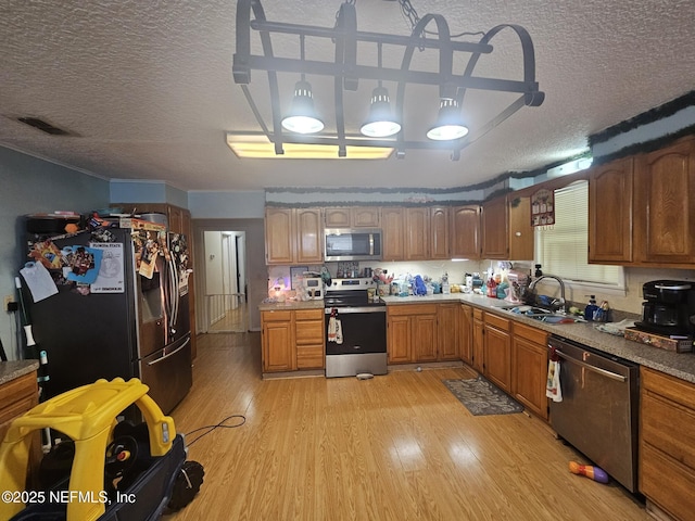 105 Owens Acres Dr, Macclenny, FL 32063 - kitchen featuring stainless steel appliances, a textured ceiling, light wood finished floors, brown cabinets, and light countertops