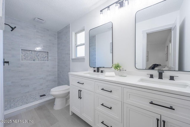 407 Lower 8th Ave S, Jacksonville Beach, FL 32250 - full bath featuring double vanity, a tile shower, a textured ceiling, and wood finished floors