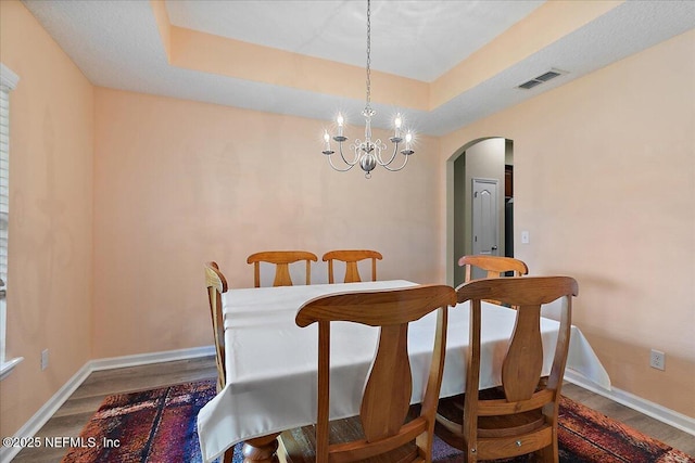 3504 Garibaldi Way, Saint Augustine, FL 32092 - dining space featuring arched walkways, a tray ceiling, wood finished floors, and a chandelier