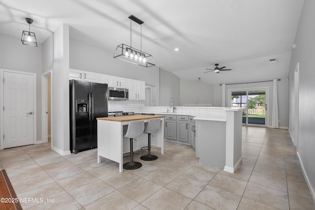 429 N Bridgestone Ave, Saint Johns, FL 32259 - kitchen featuring black refrigerator with ice dispenser, stainless steel microwave, a breakfast bar, light tile patterned floors, and vaulted ceiling
