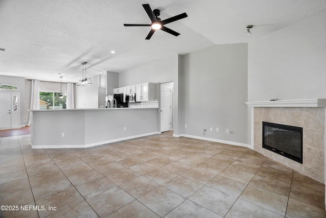 429 N Bridgestone Ave, Saint Johns, FL 32259 - unfurnished living room with light tile patterned flooring, ceiling fan, a tile fireplace, a textured ceiling, and vaulted ceiling
