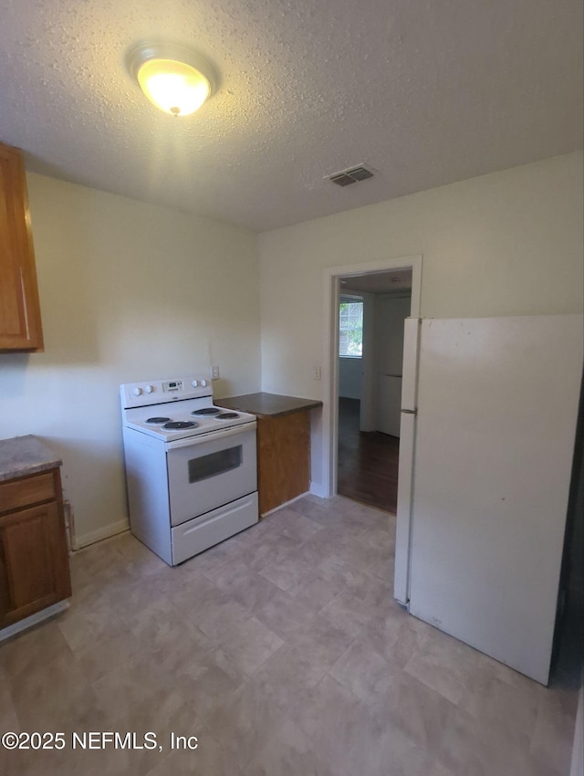 3136 Post St, Jacksonville, FL 32205 - kitchen with white appliances, brown cabinetry, light floors, and a textured ceiling