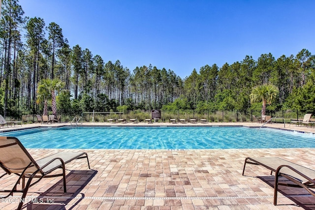 78262 Saddle Rock Rd, Yulee, FL 32097 - community pool featuring a patio area and view of wooded area