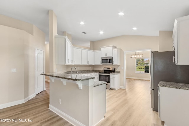 78262 Saddle Rock Rd, Yulee, FL 32097 - kitchen featuring stainless steel appliances, a peninsula, a breakfast bar area, dark stone counters, and white cabinets