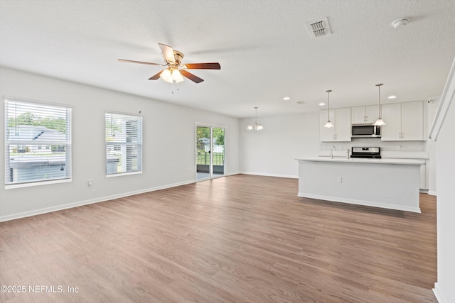 82 Birchfield Ln, Saint Augustine, FL 32092 - unfurnished living room with a ceiling fan, light wood-type flooring, a chandelier, recessed lighting, and a textured ceiling