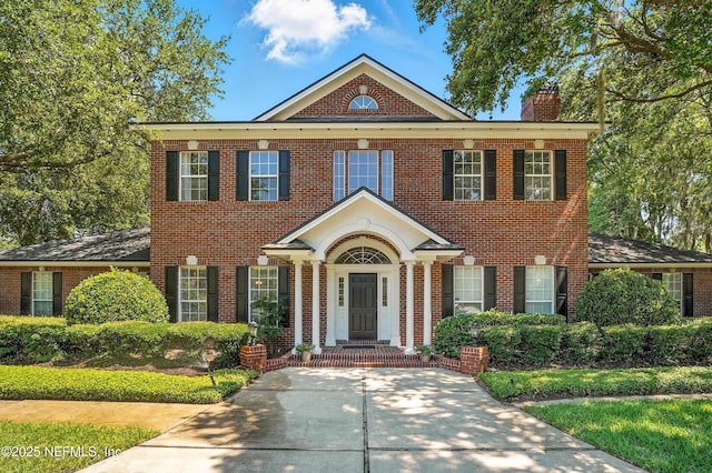 8483 Stables Rd, Jacksonville, FL 32256 - colonial inspired home with a chimney and brick siding