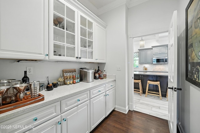 8483 Stables Rd, Jacksonville, FL 32256 - bar featuring stainless steel microwave, crown molding, dark wood-style flooring, and tasteful backsplash