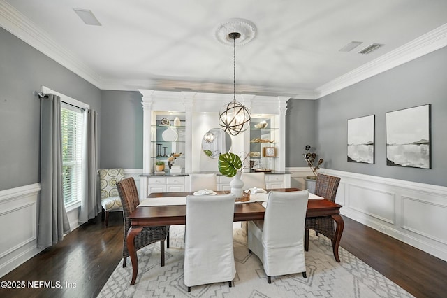 8483 Stables Rd, Jacksonville, FL 32256 - dining area with wood finished floors, ornamental molding, a decorative wall, and wainscoting