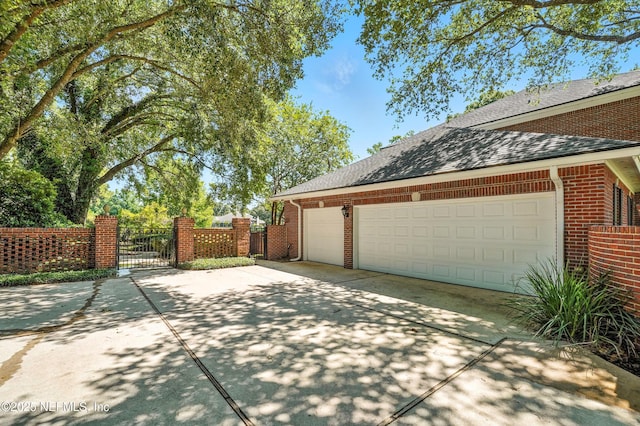 8483 Stables Rd, Jacksonville, FL 32256 - view of property exterior featuring a gate, concrete driveway, brick siding, and a garage