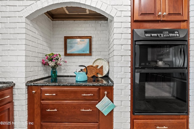 1786 Selva Marina Dr, Atlantic Beach, FL 32233 - kitchen with black appliances, dark stone countertops, range hood, brick wall, and brown cabinetry