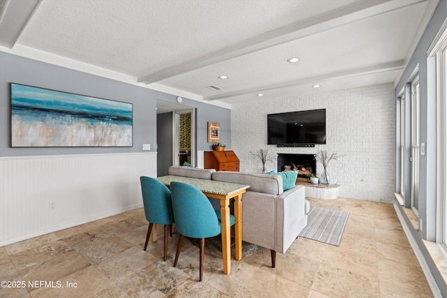 1786 Selva Marina Dr, Atlantic Beach, FL 32233 - living room featuring brick wall, beamed ceiling, stone tile floors, a fireplace, and a textured ceiling