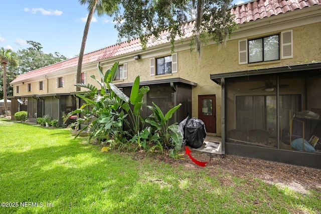 5811 Atlantic Blvd Unit 25, Jacksonville, FL 32207 - back of property featuring a sunroom, stucco siding, a yard, and a tile roof