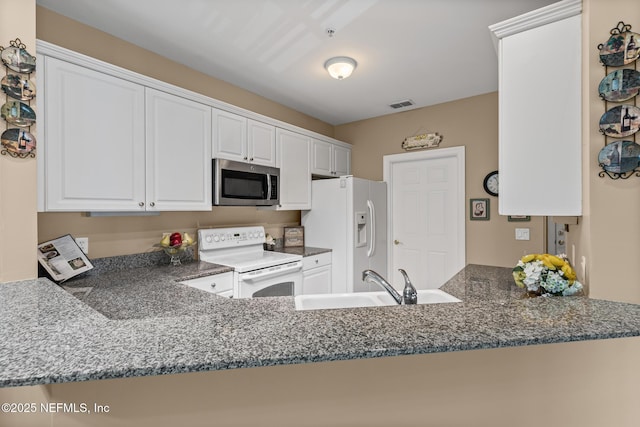 160 Legendary Dr Unit 204, Saint Augustine, FL 32092 - kitchen featuring white appliances, a peninsula, dark stone countertops, and white cabinetry