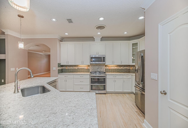 1356 Barrington Cir, Saint Augustine, FL 32092 - kitchen with appliances with stainless steel finishes, arched walkways, white cabinetry, hanging light fixtures, and crown molding